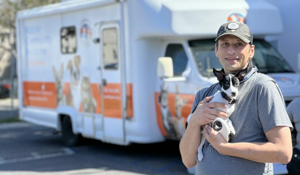 C.A.R.E.4Paws Mobile Clinic with a man holding a black and white puppy