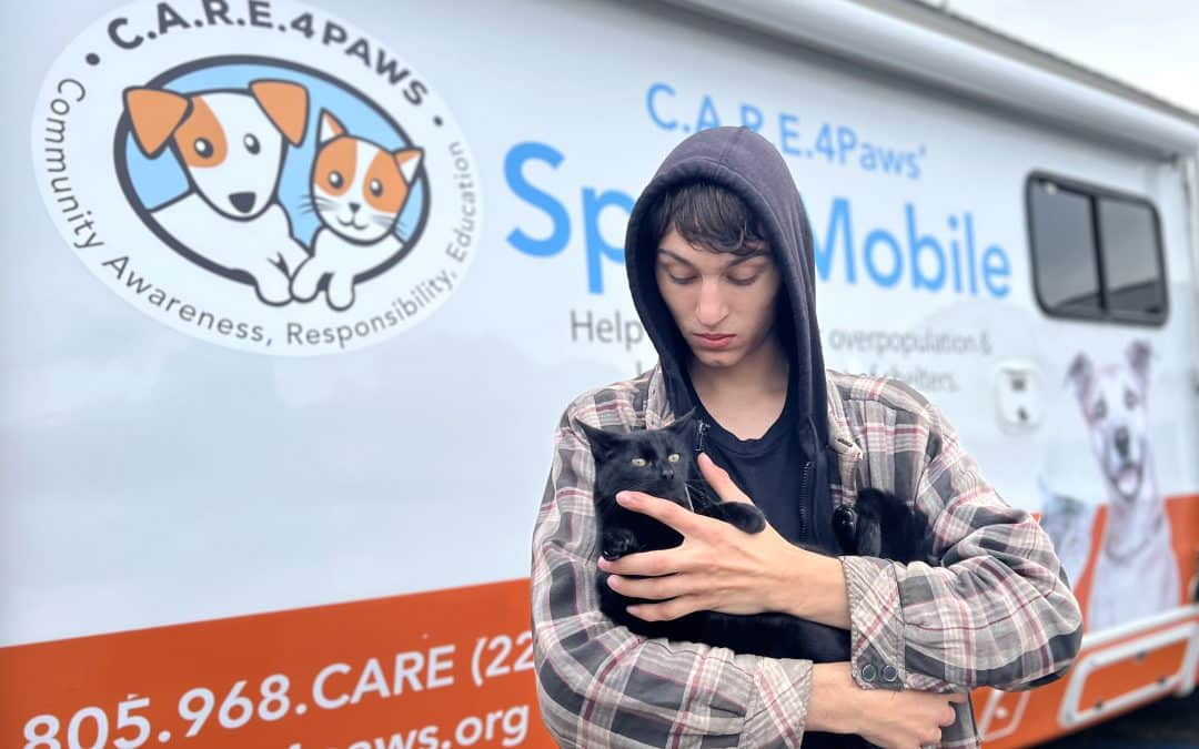 Boy holding cat in front of C.A.R.E.4Paws Mobile Clinic