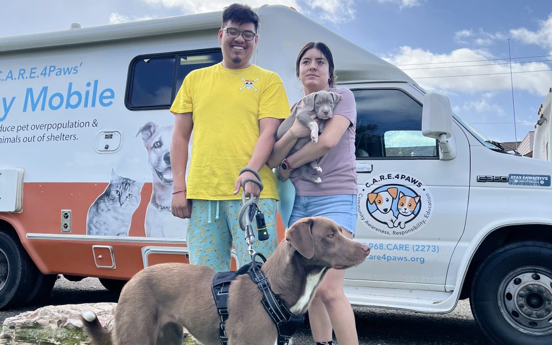 A couple with their two dogs standing in front of the C.A.R.E.4Paws mobile clinic